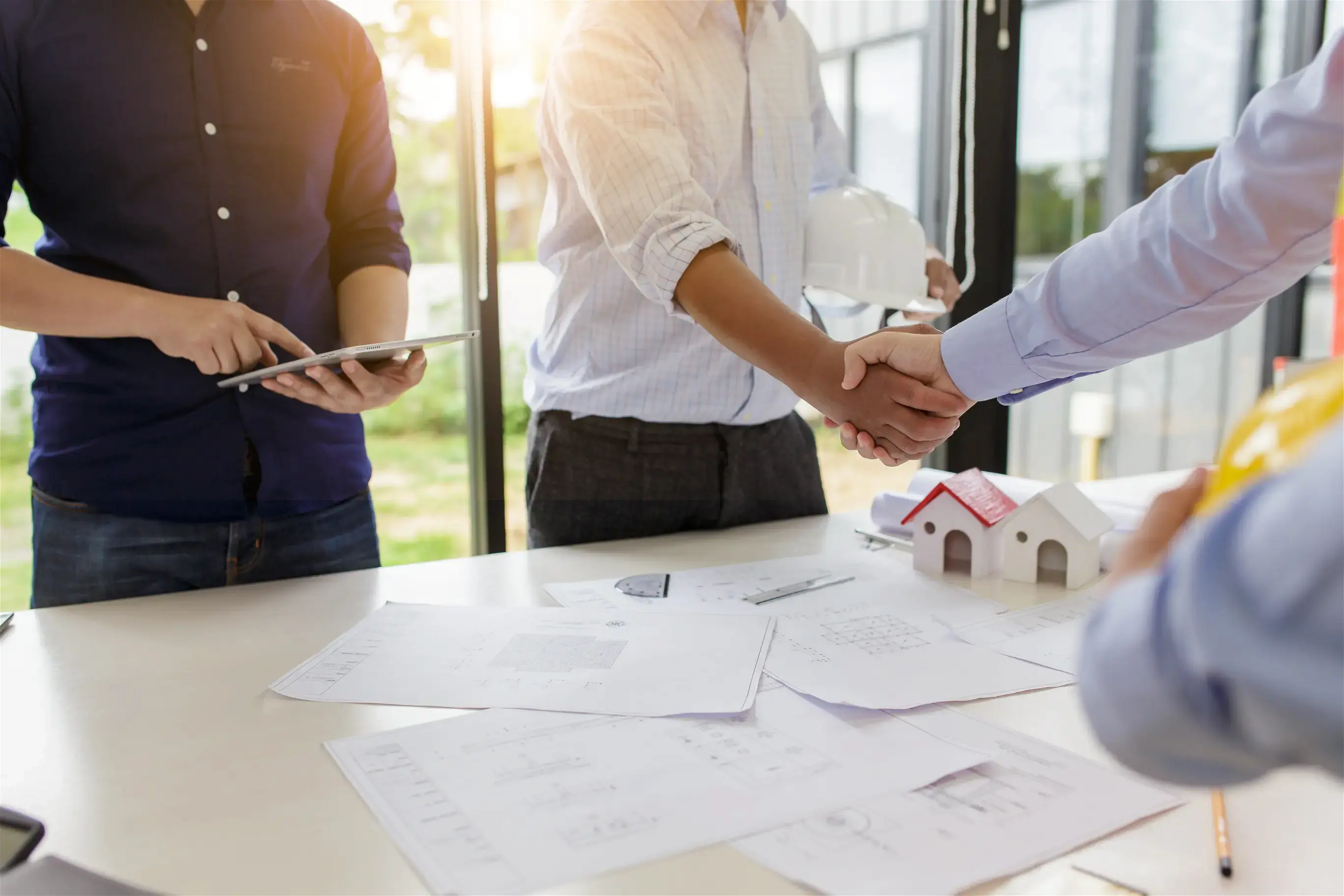 Des personnes se serrent la main autour d'une table pour une vente immobilière