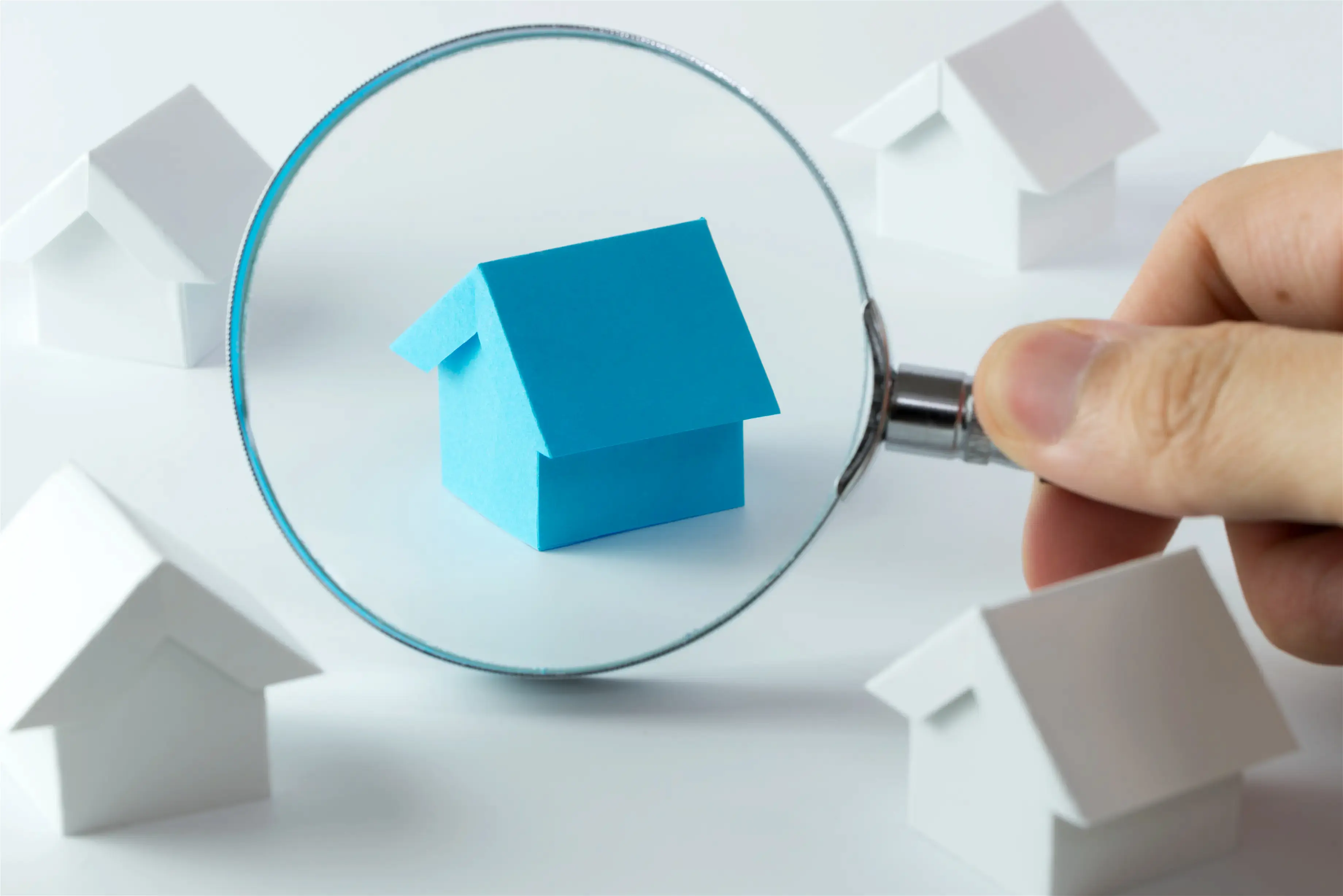 une personne regarde une petite maison avec une loupe